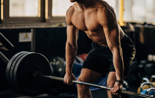 istock Muscular shirtless man exercising with weights in gym 1299288279