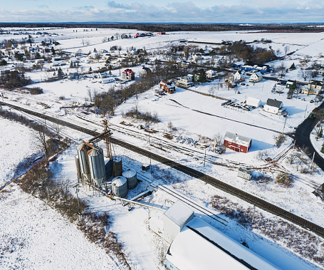 Aerial drone view of disused grain silos at the edge of a rail line.
