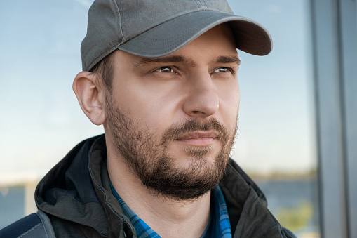 Portrait of serious confident bearded man in baseball cap looking into the distance