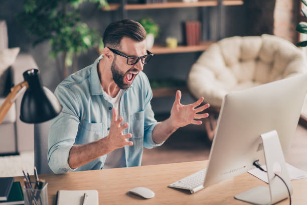 istock Photo portrait of guy screaming at computer screen on table in modern industrial office indoors 1299290084