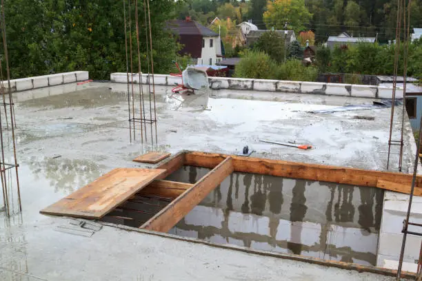 view of the hardened concrete slab base between floors with wheelbarrow. Construction of a country house made of foam blocks