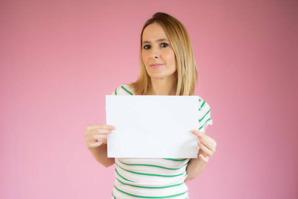 istock Young woman keeps with hand at the copy space, isolated over pink background. 1299291377