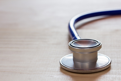 close up blue stethoscope on wood table or office desk with copy space for design. Health concept