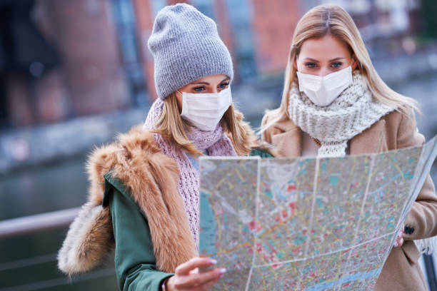 istock Two women wearing masks and holding map while sightseeing Gdank in Poland 1299293132