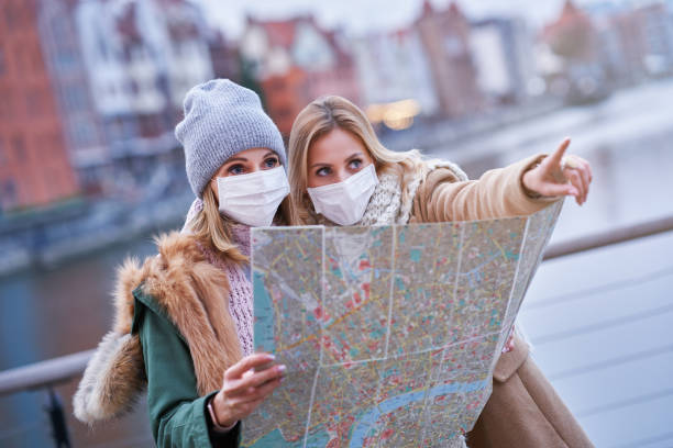 istock Two women wearing masks and holding map while sightseeing Gdank in Poland 1299293180