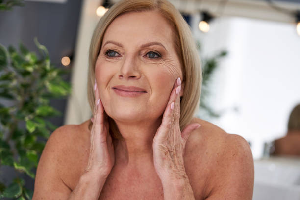 istock Senior woman using anti wrinkle cream in the bathroom 1299294908