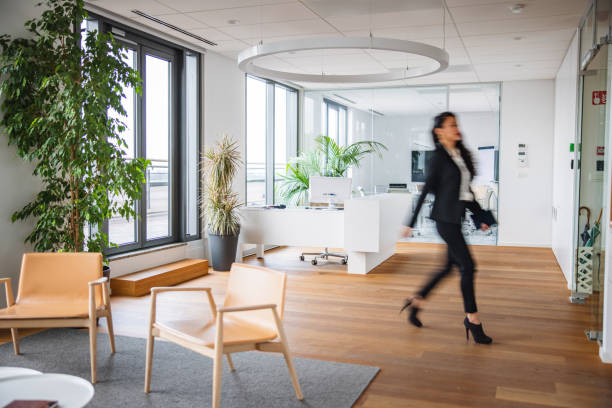Full length side view with blurred motion of well-dressed corporate professional in early 30s on the move through office.