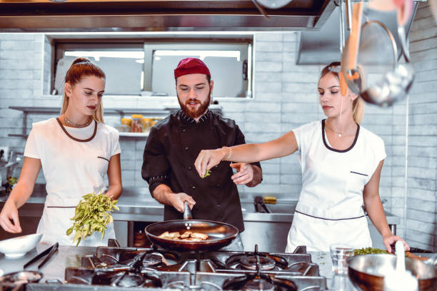 istock Female Putting Spices In Male Chef's Dish 1299299052