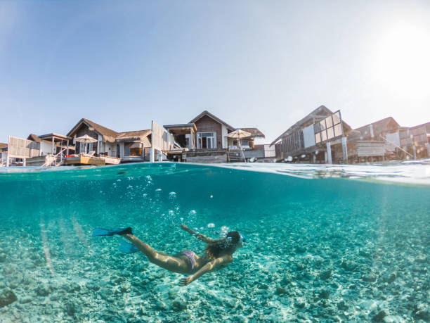 Woman dives in tropical sea, split screen underwater shot, overwater villas on background She explores the reef around the atoll in the Maldives, people on vacations, she adventures underwater vacation rental mask stock pictures, royalty-free photos & images