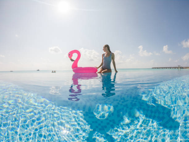 woman relaxes with inflatable flamingo in swimming pool - inflatable raft nautical vessel sea inflatable imagens e fotografias de stock
