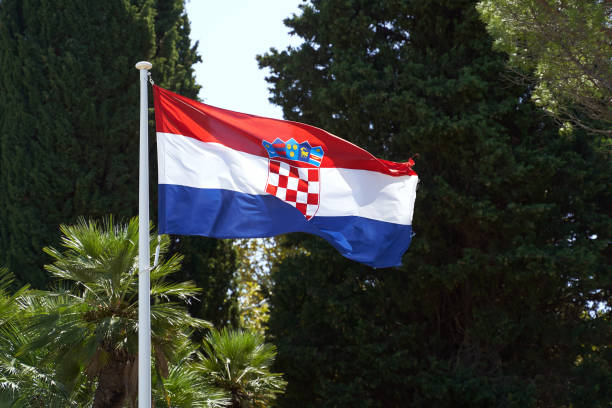 istock Waving flag of Croatia on summer trees background 1299299458