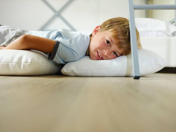 istock Child in pajamas sleeping in his bed without blankets, illuminated by the light that filters through the window 1299299797