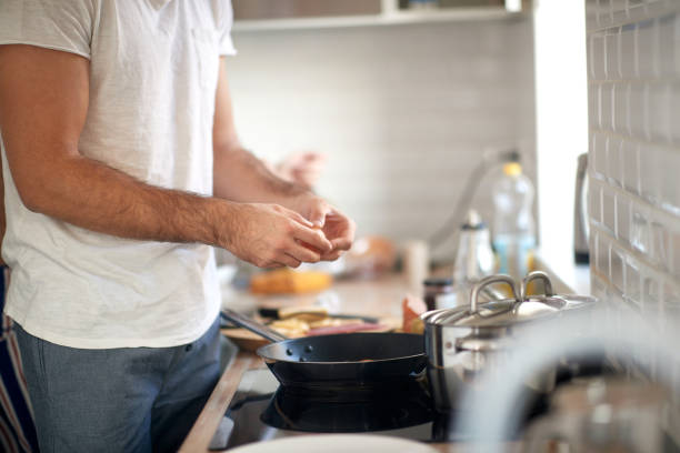 istock A young guy making a meal. Kitchen, food, home, cooking 1299301809