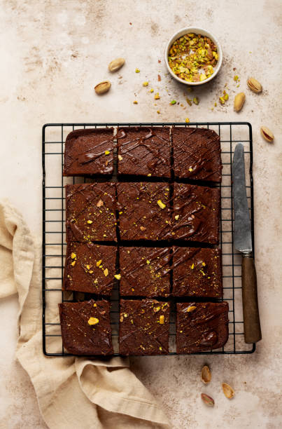 istock Chocolate squares with pistachio nuts and strawberries on a metal stand on a light stone background, top view, horizontal composition. Flat lay. 1299301818