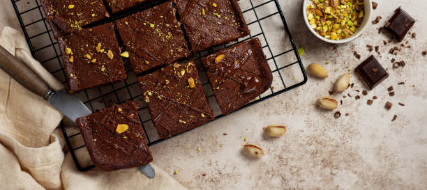 istock Chocolate squares with pistachio nuts and strawberries on a metal stand on a light stone background, top view, horizontal composition. Flat lay. 1299301931