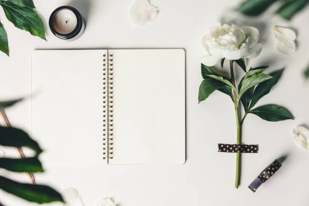 istock Flat-lay of Beautiful peony flower taped on white background and open notebook 1299304693
