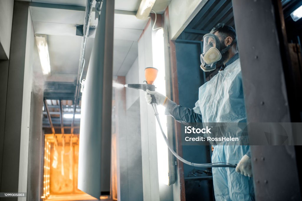 Powder coating process of metal products Painter in protective wear paints metal products with powder paint. Powder coating process at the manufacturing. High quality photo Coating - Outer Layer Stock Photo