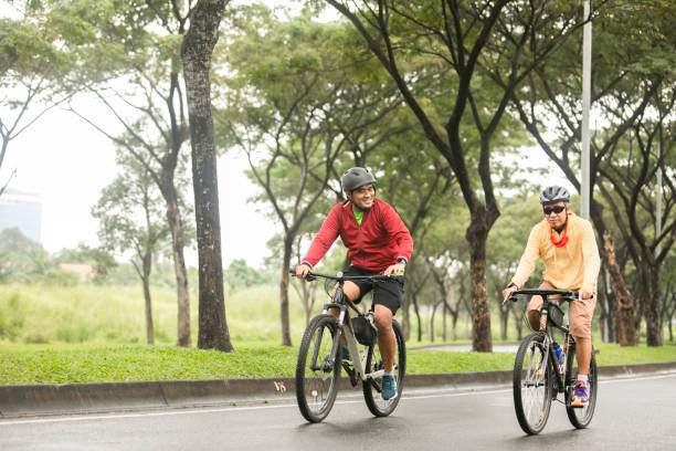 padre e hijo andar en bicicleta por la calle juntos - cycling senior adult sports helmet men fotografías e imágenes de stock