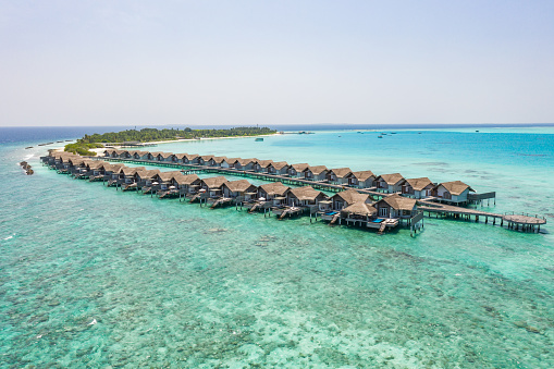 High angle view, luxury overwater villas on reef lagoon.