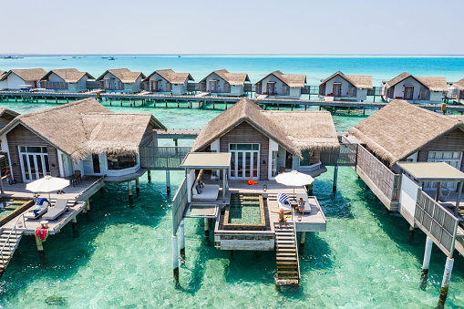 High angle view, luxury overwater villas on reef lagoon.