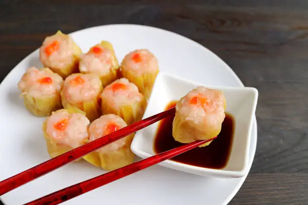 Photo of Shrimp and Pork Filled Chinese Steamed Dumpling Being Dipped in Soy-vinegar Sauce