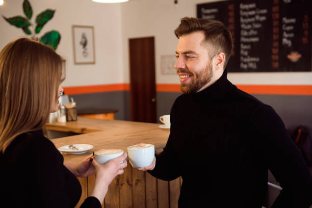 istock Beautiful Woman And Handsome Man Drinking Coffee While Spending Time In Coffee Shop. 1299307709