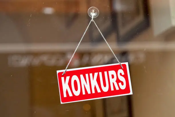 Red sign hanging at the glass door of a shop with written in it in German "Konkurs" meaning in English "Bankruptcy".