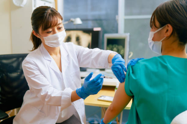 travailleuse médicale se faisant vacciner dans le bureau du médecin - injecting flu virus cold and flu doctors office photos et images de collection