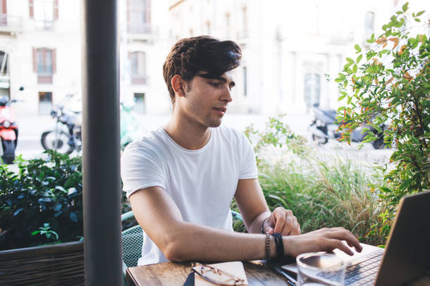 istock Brunette young male student typing on laptop computer making research for education online course, skilled caucasian man freelancer working on project remotely sitting on cafe terrace with technology 1299309073