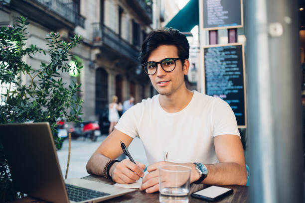 istock Charismatic man writing in notebook in sidewalk cafe 1299309086