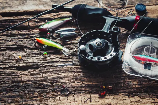 Photo of fishing rod and bait for fishing on wooden background