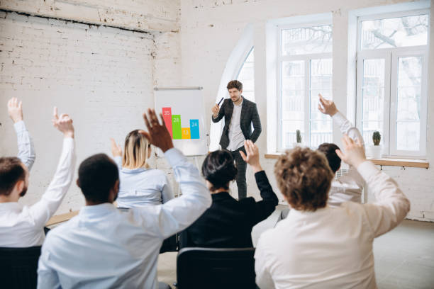 istock Male speaker giving presentation in hall at workshop. Audience or conference hall. Rear view of unrecognized participants. 1299311911