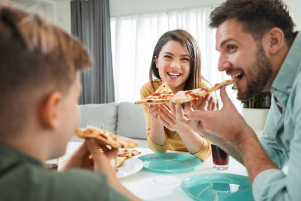 istock Smiling Family enjoy pizza 1299313198