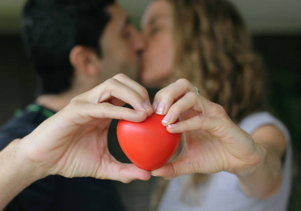 istock Couple kissing while holding red heart 1299313791