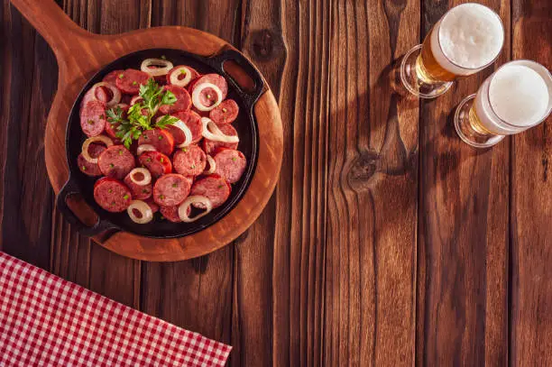 Sliced smoked fried calabrese sausage with onion and beer - Brazilian appetizer top view with space copy