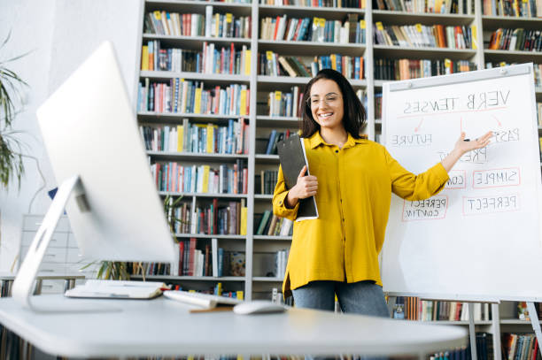 istock Online training. Young smart smiling female teacher conducts online lesson for students via video conference showing information on flipchart 1299316642