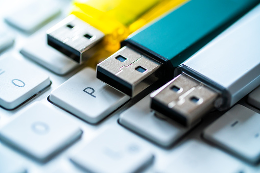 a row of colorful usb sticks lie on the computer keyboard. data distributed and saved on various data storage devices