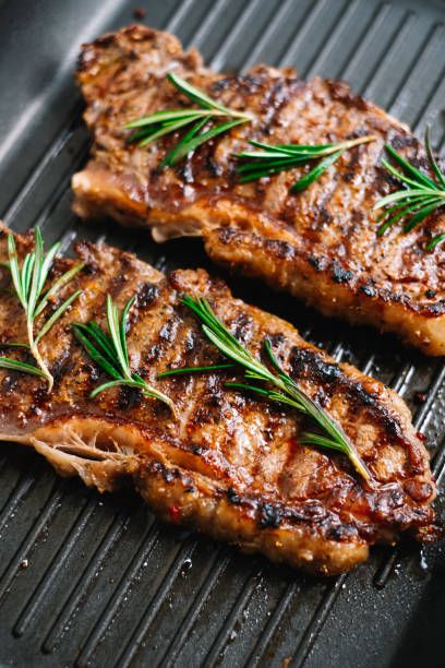 istock Grilled beef steak with rosemary in black grill pan on the table. 1299319602
