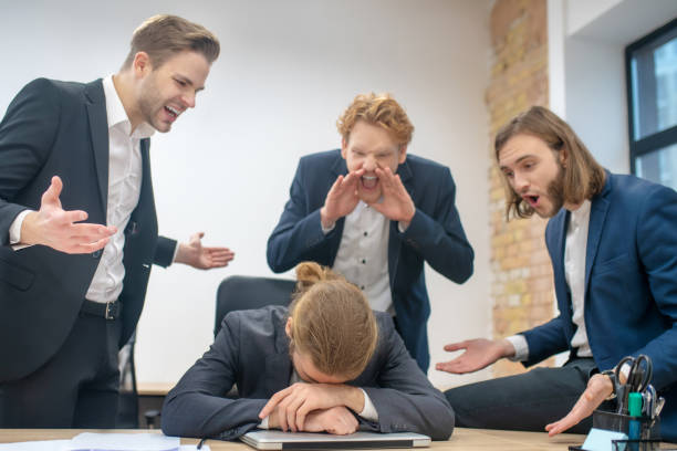 istock Man with bowed head and three screaming colleagues 1299319749