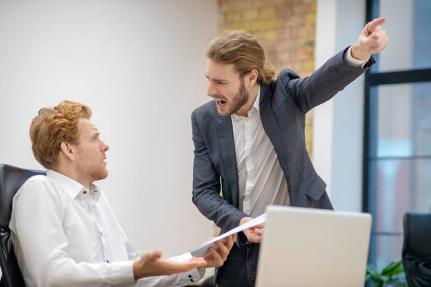 istock Screaming man pointing with hand and bewildered colleague 1299319762