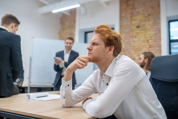 istock Thinking man in profile at table and colleagues 1299319790