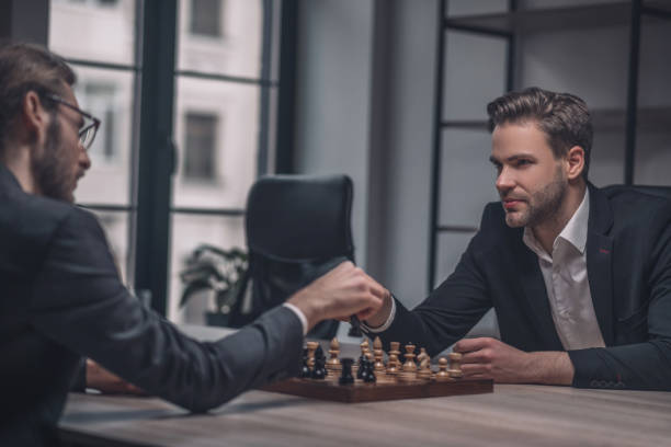 istock Two players holding hands over chessboard 1299319809
