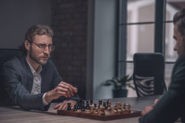 istock Man with chess piece looking at opponent 1299319819