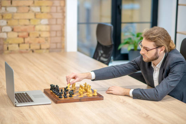 istock Man rearranging chess piece in front of laptop 1299319849