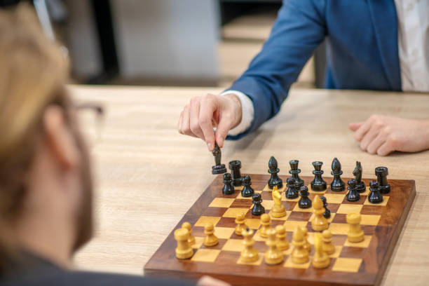 istock Male hand with black horse over a chessboard 1299319850