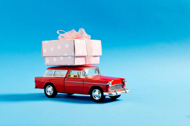 istock Retro Red Toy Car Carrying - Delivering Gift Box On Blue Background 1299321346