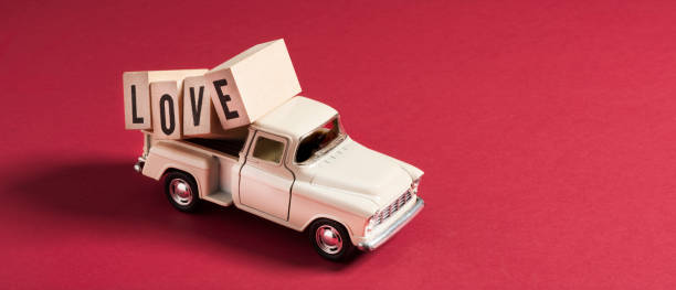 istock Retro Toy Car Delivering LOVE Cubes - Red Background 1299321912