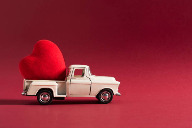 retro toy car delivering craft heart for Valentine's day on red background. Valentines Day concept.