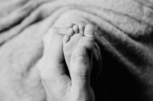 A close up image of a newborn's tiny foot in dad's hand.
