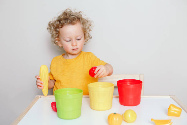 istock Toddler playing with learning toys at home or kindergarten. Baby sorting organising objects blocks with specific color. Early age education. Kids hand brain development activity for preschoolers. 1299323060